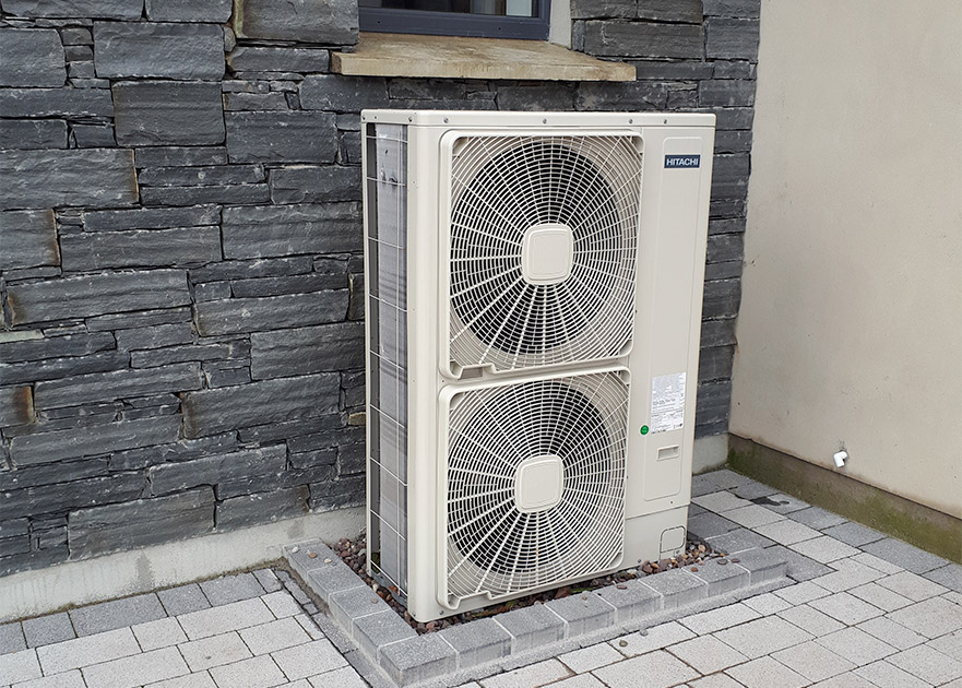air to water heat pump placed next to a property with a brick wall