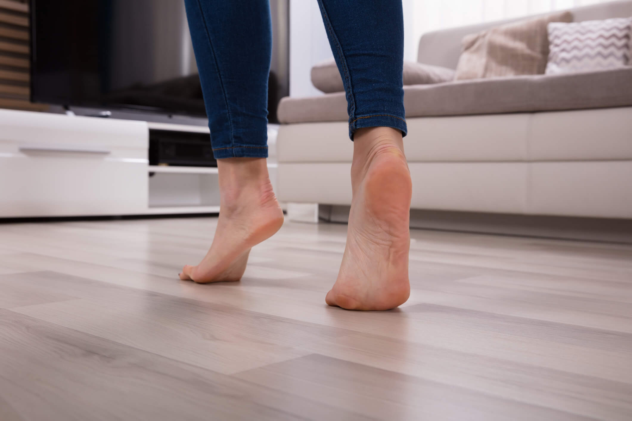 person walking barefoot on laminate floor to represent underfloor heating concept