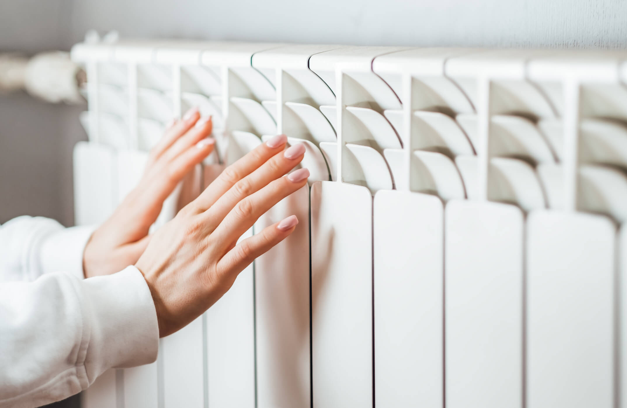 close up of woman holding hands up to radiator