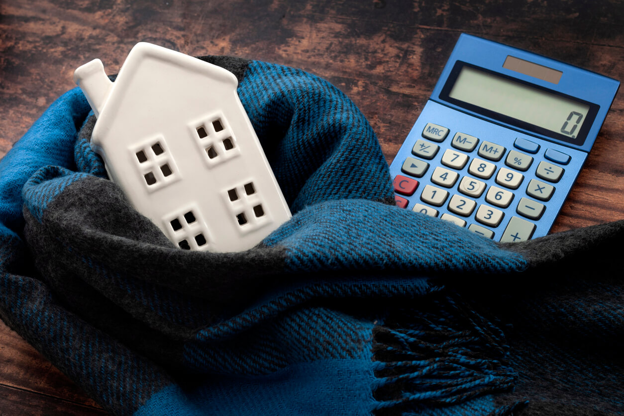 calculator and house wrapped in scarf to represent the cost of heating