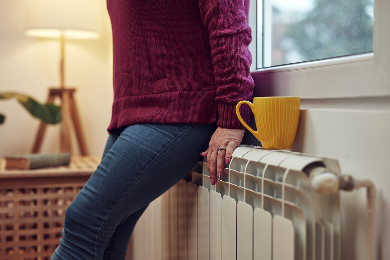 woman resting on radiator with yellow mug next to her