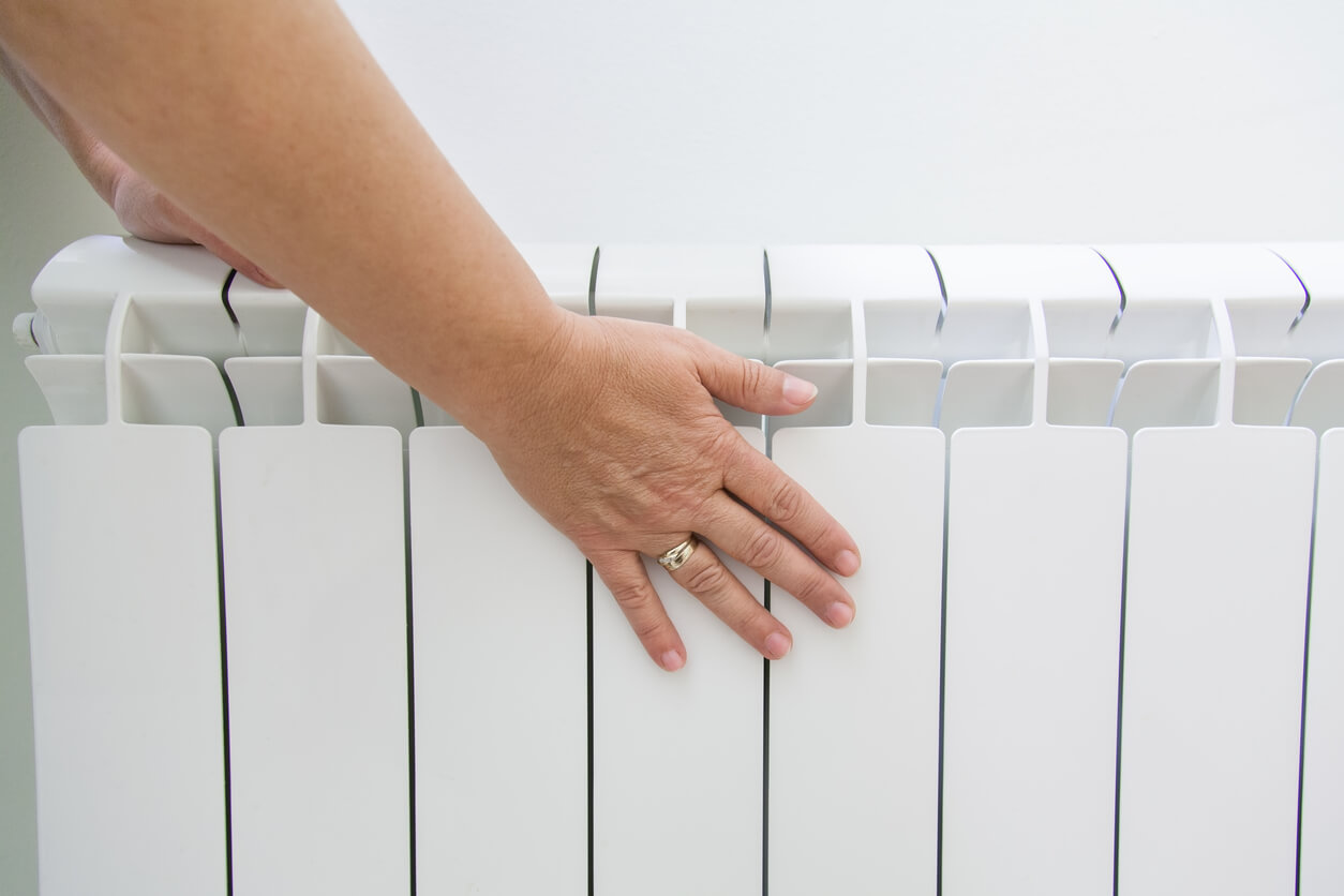 person placing hand on radiator to check whether it's heated