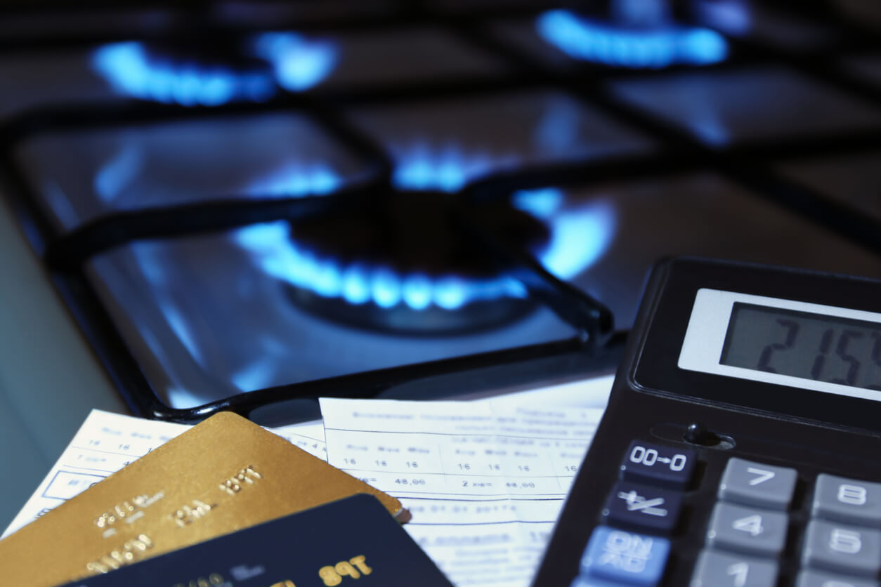 bank cards and calculator next to burning gas stove to represent fossil fuel energy crisis