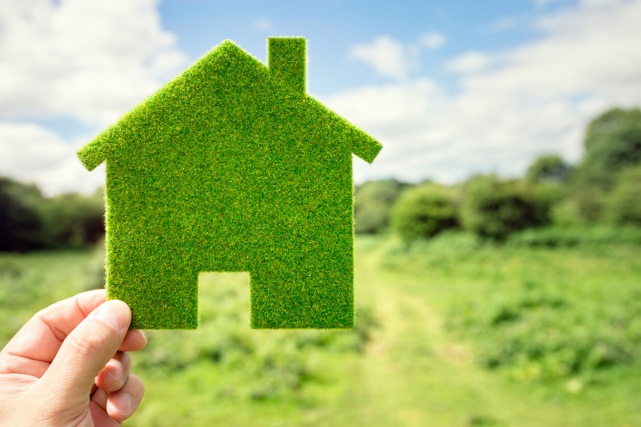 hand holding up green house symbol to represent eco friendly home