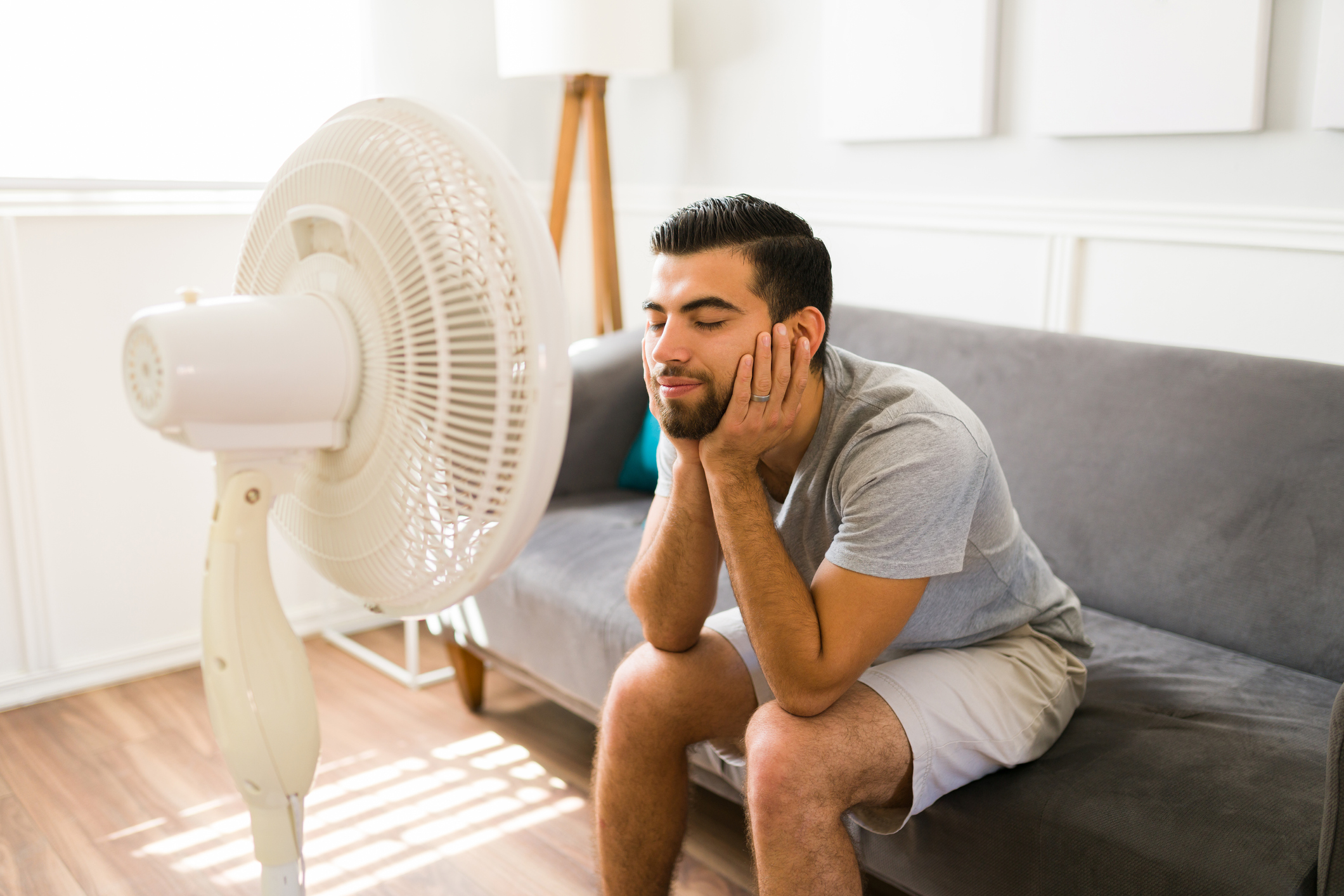 a man sitting on the sofa in front of a fan