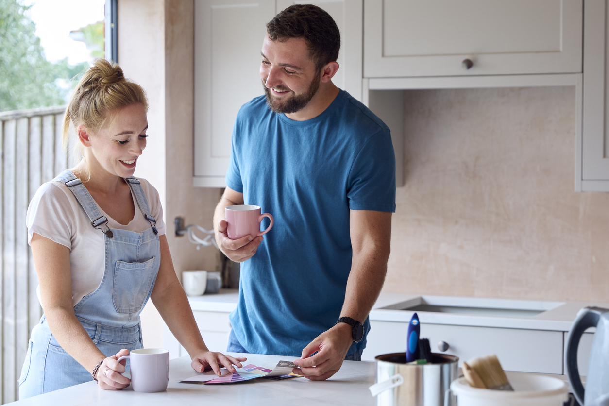 man and woman look at colour charts in kitchen